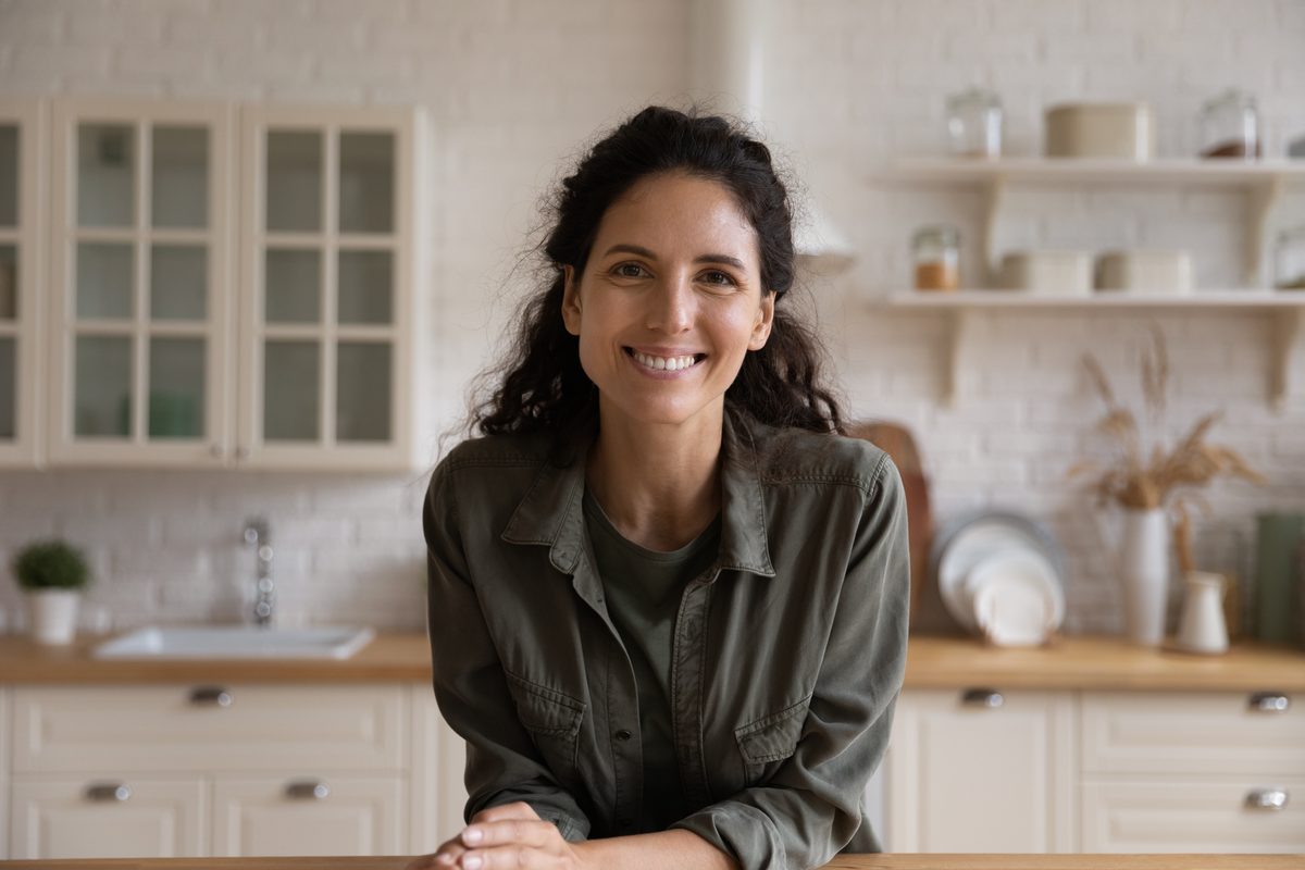 Mujer latina sonriendo en su cocina, transmitiendo bienestar y confianza